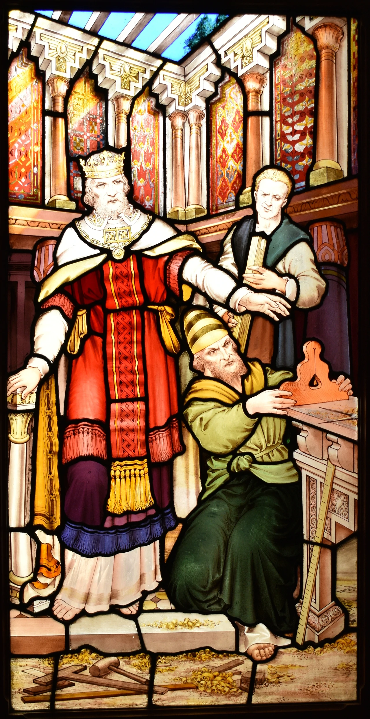 Stained glass window, depicting a wealthy man wearing a crown, and two craftsmen working on a project